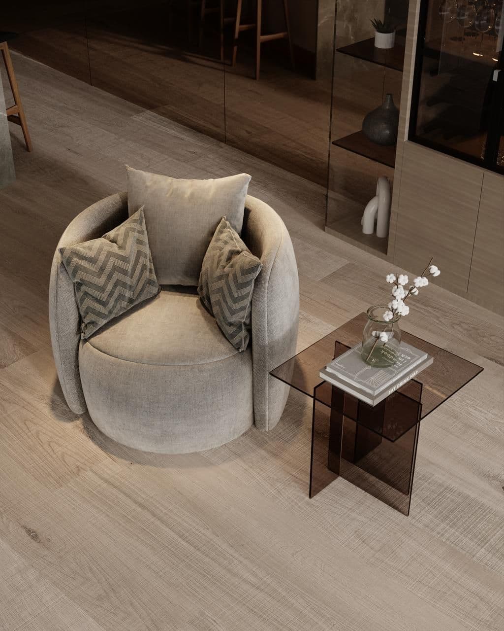 A plush, round armchair with two decorative pillows sits next to a small glass side table.